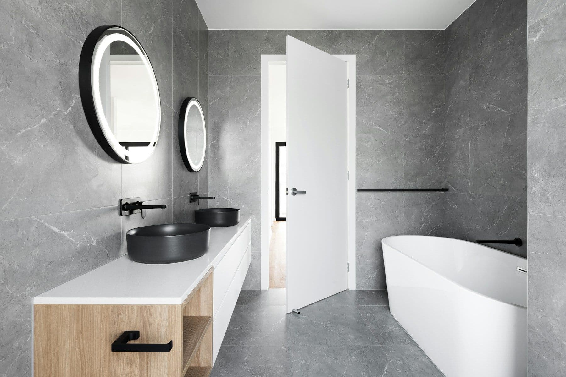 Grey stone bathroom with backlit mirror, vessel basin and freestanding tub